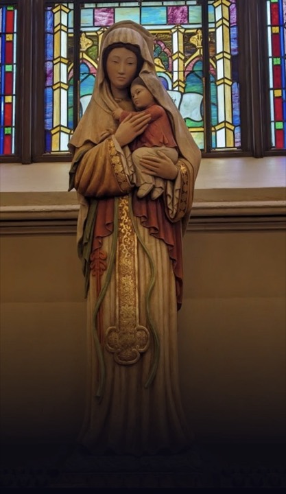 Madonna and Child statue before stained glass